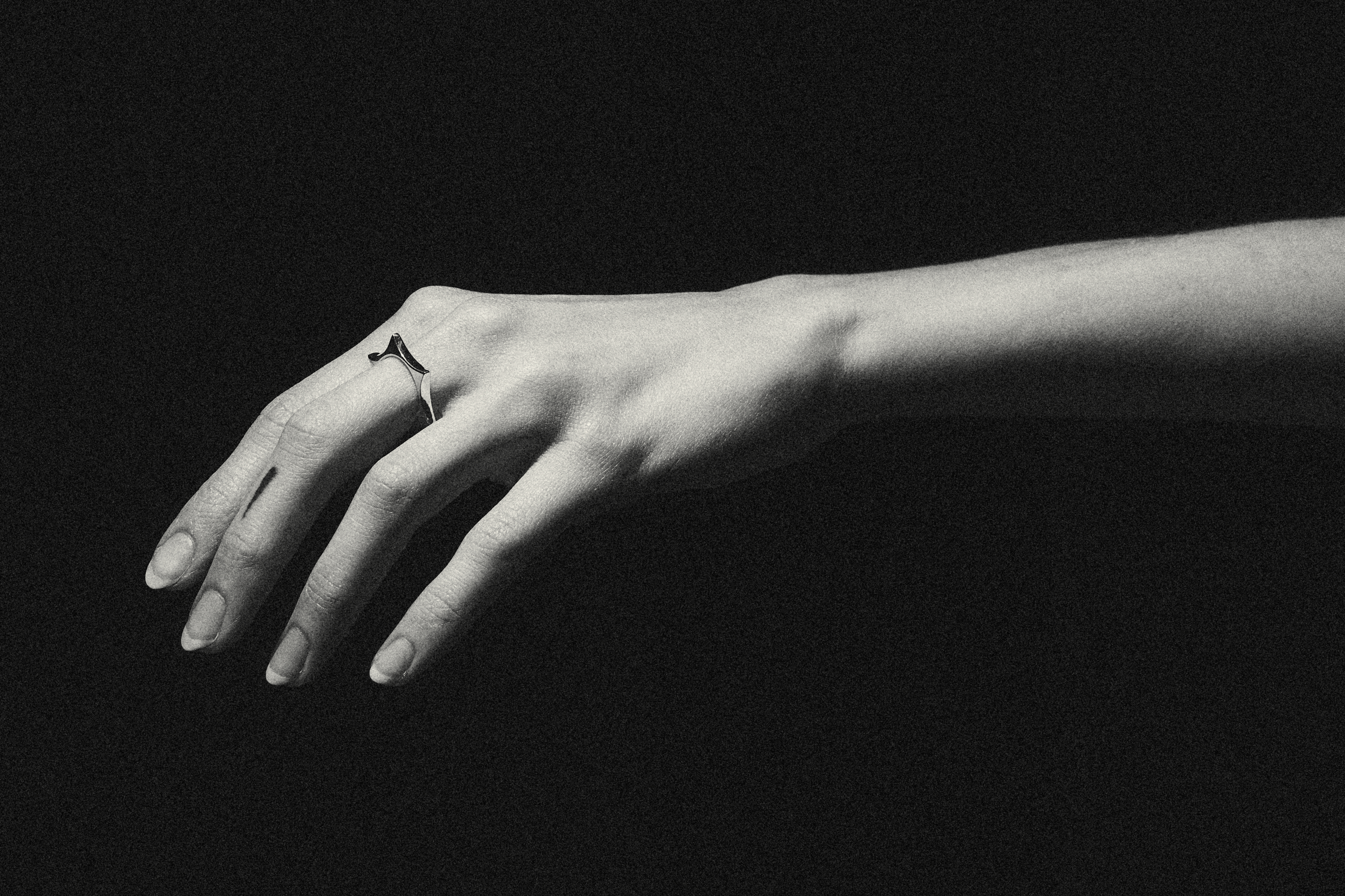 Black and white photograph of a hand wearing a sculptural ring.